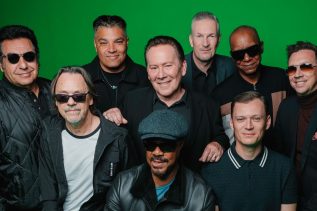 UB40 con Ali Campbell en vivo sobre el escenario, interpretando clásicos del reggae ante un teatro lleno