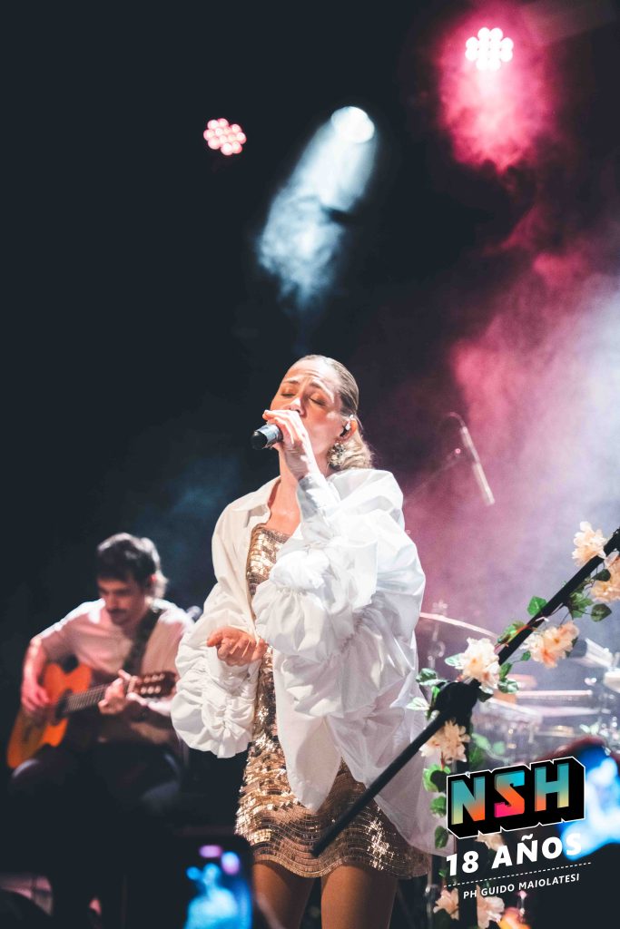 Rocío Igarzábal interpretando canciones de Volare en vivo en La Tangente
Escena del show de Rocío Igarzábal con vestuario etéreo durante Volare
El público emocionado en el recital de Rocío Igarzábal en Buenos Aires
Dueto entre Rocío Igarzábal y El Purre en La Tangente
Cambio de vestuario de Rocío Igarzábal en su presentación de Volare
Potra y Rocío Igarzábal en una interpretación íntima durante el show
Vista del escenario iluminado durante el concierto de Volare en La Tangente
Rocío Igarzábal celebrando con el público al final de su show en vivo
Momentos festivos del recital de Rocío Igarzábal con coreografía y luces
Detalle del EP Volare presentado por Rocío Igarzábal en La Tangente